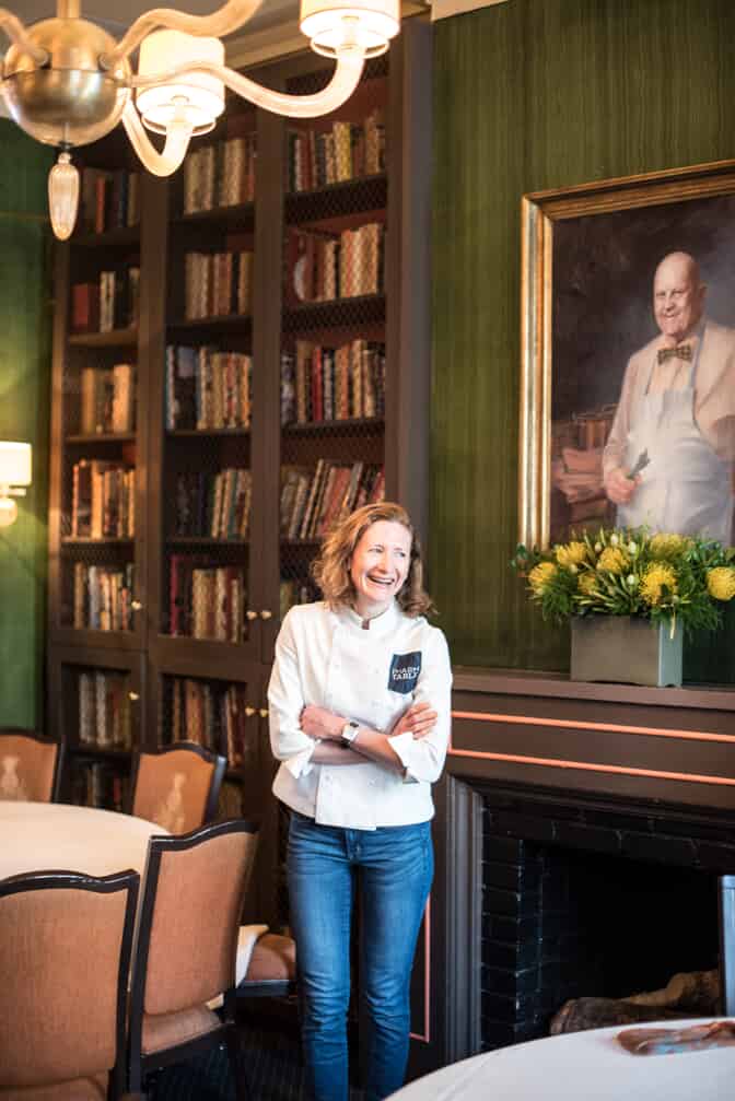 Woman in chef jacket with books behind her