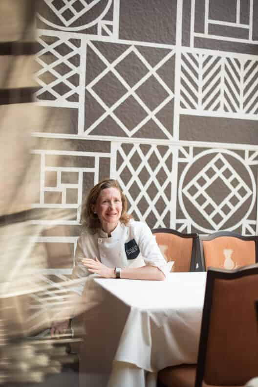 Woman in chef jacket sitting at a reaturant